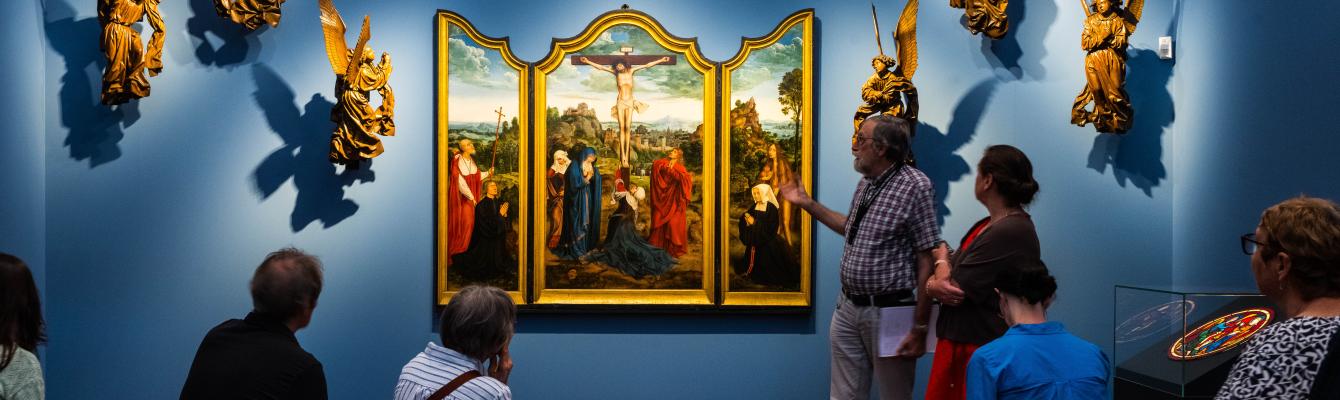 Een groep mensen kijkt naar het drieluik Calvarie met stichterspaar