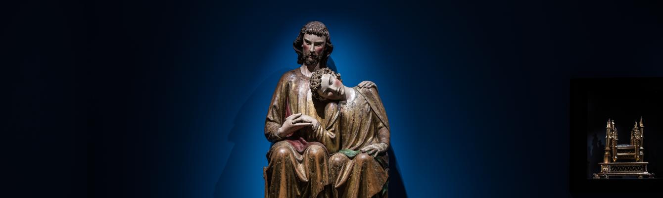 Een houten sculptuur van Johannes die zijn hoofd laat rusten op de schouder van Jezus.