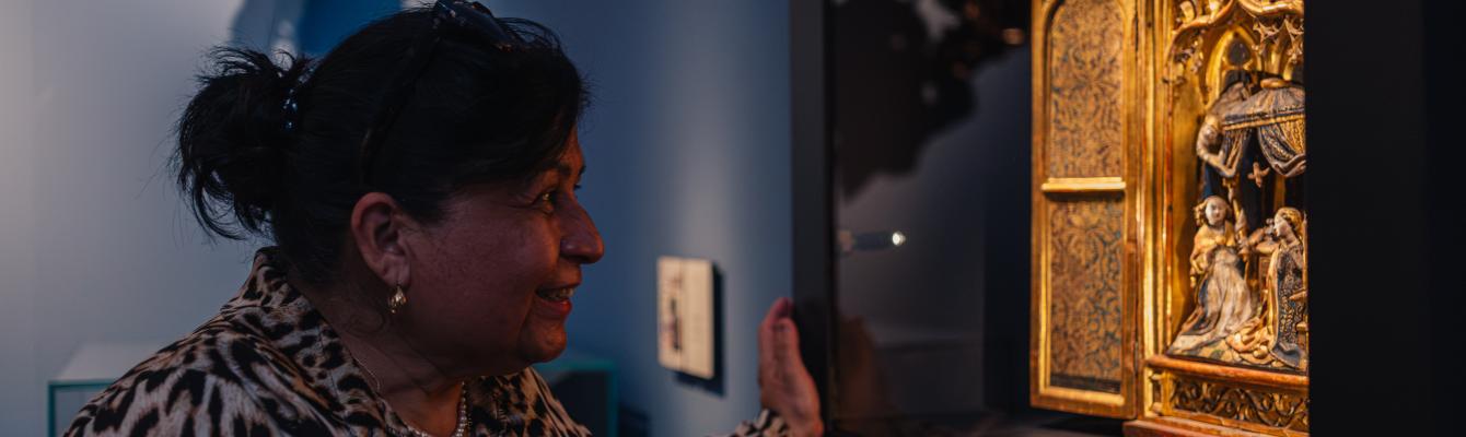 Een vrouw kijkt naar een altaarstuk in een museumzaal.