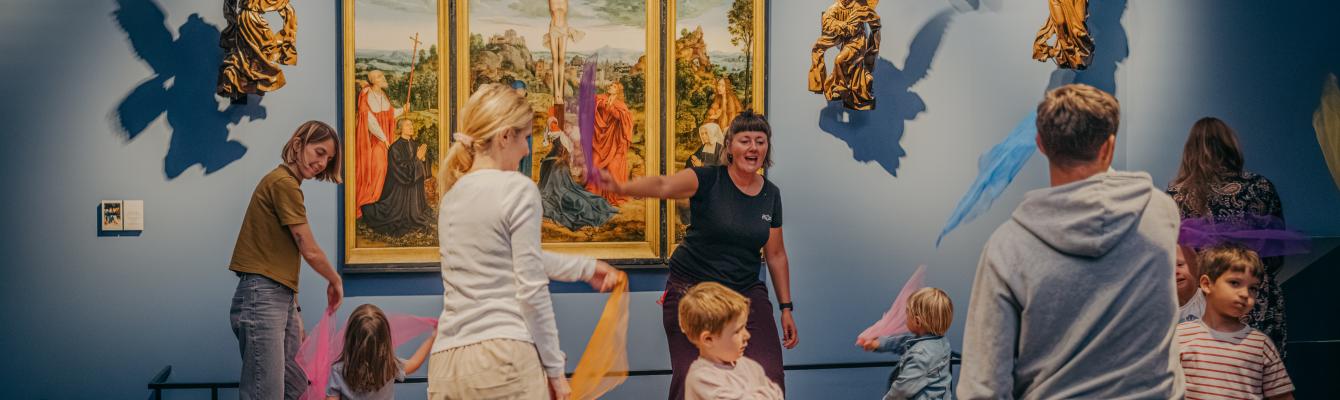 Kinderen en volwassenen gooien met slingers in een museumzaal.