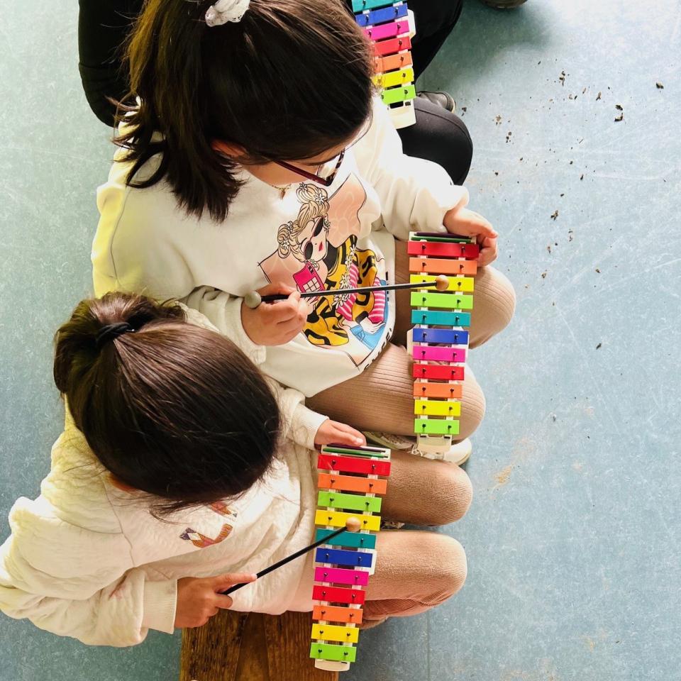 Twee kleine kinderen maken muziek op een tokkelinstrument.