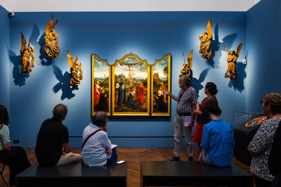 Een groep mensen kijkt naar het drieluik Calvarie met stichterspaar