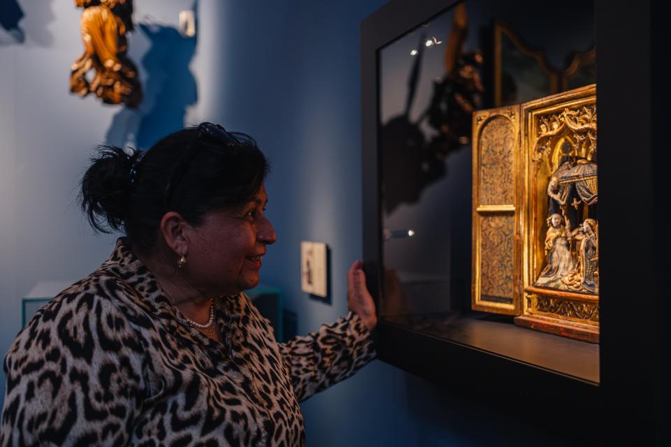 Een vrouw kijkt naar een altaarstuk in een museumzaal.