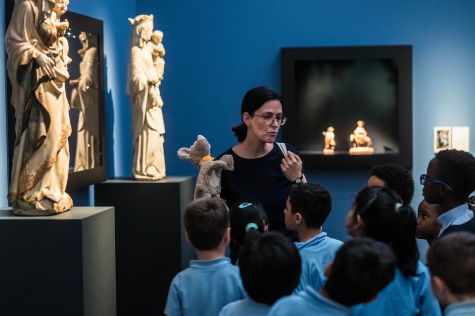Een vrouw leidt kinderen rond in een museumzaal.