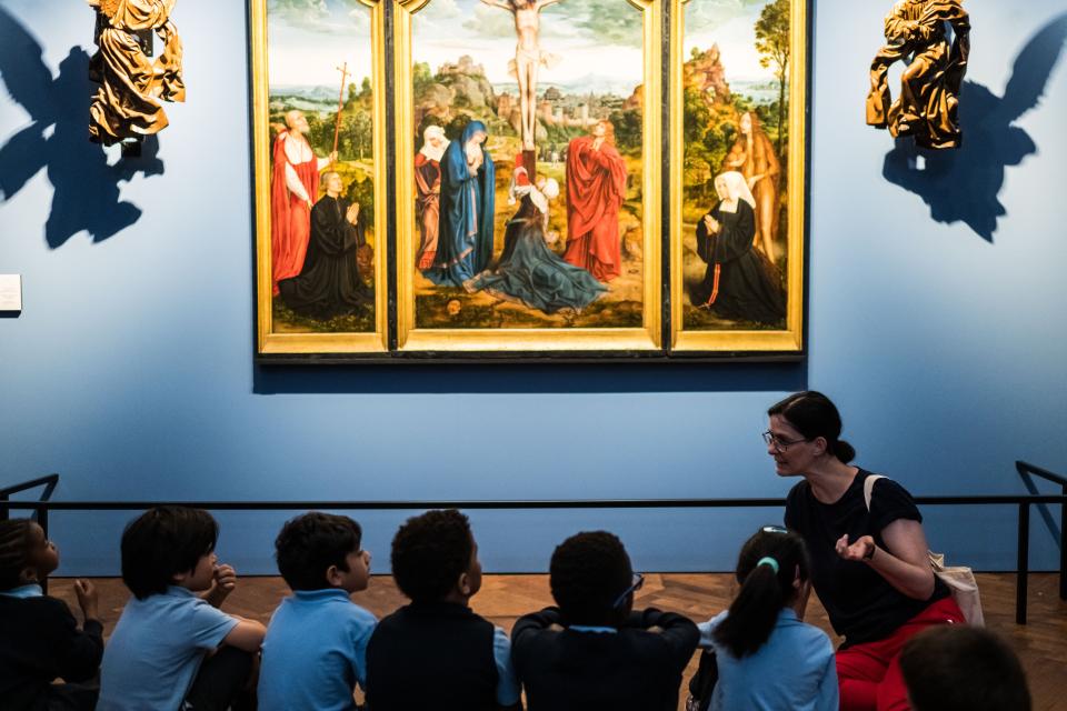 Een groep kinderen kijkt naar een schilderij waarop de kruisiging van Jezus staat afgebeeld.