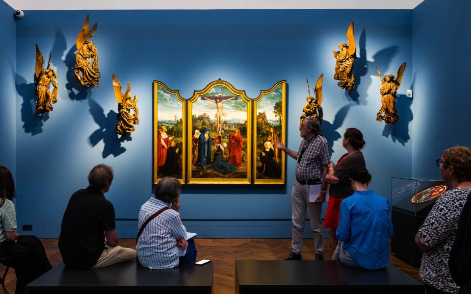 Een groep mensen kijkt naar het drieluik Calvarie met stichterspaar