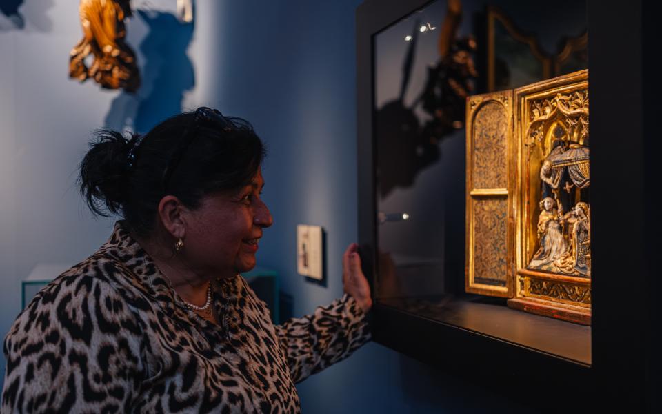 Een vrouw kijkt naar een altaarstuk in een museumzaal.