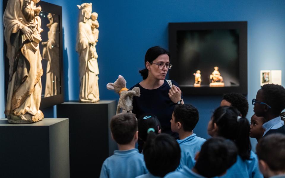 Een vrouw leidt kinderen rond in een museumzaal.