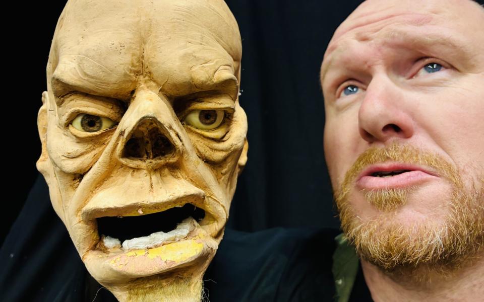 Het gezicht van een man naast het 'gezicht' van een pop, die hij in de hand houdt.