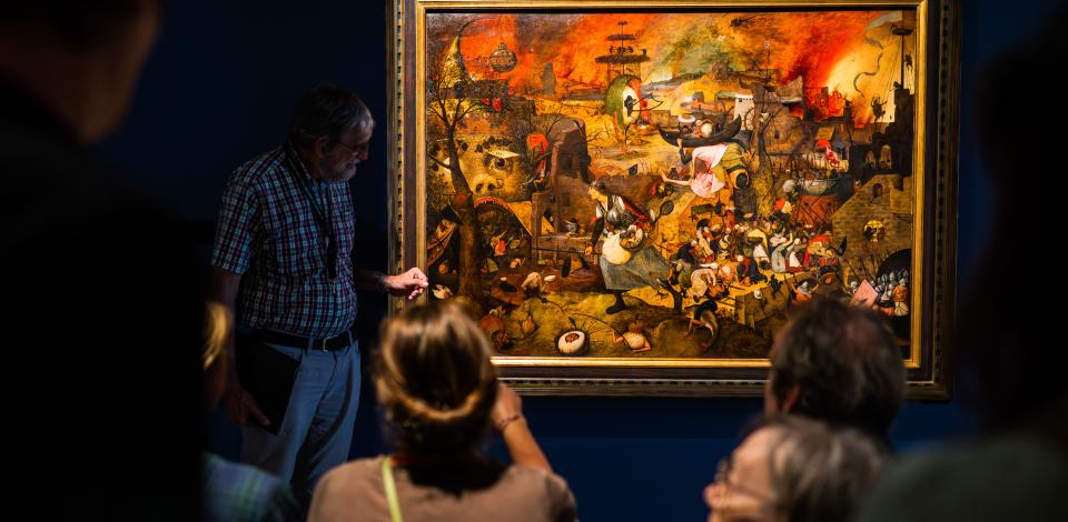 Mensen kijken naar het schilderij 'Dulle Griet' van Pieter Bruegel de Oude.