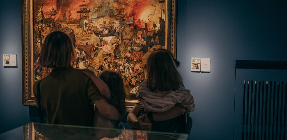 Een moeder en haar kinderen kijken samen naar het schilderij 'Dulle Griet'.